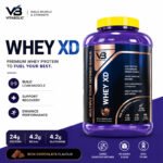 "VB Nutrition Whey XD premium whey protein powder container with chocolate flavor packaging, highlighting 24g protein, 4.2g BCAAs, 4.2g glutamine, muscle recovery, and lean muscle support on a white and purple product label."